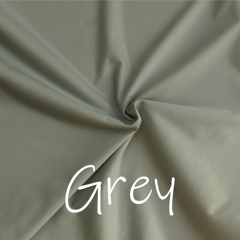 May include: A close-up of a smooth, grey fabric with a slight sheen. The fabric is folded and draped, creating soft folds and curves. The word "Grey" is written in white text on the fabric.