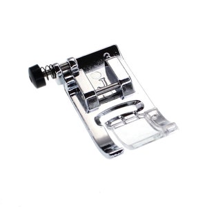 May include: A silver sewing machine foot with a clear plastic guide and a spring-loaded adjustment knob. The foot is labelled with the letter "J".