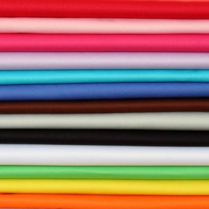 May include: A stack of fabric swatches in various colors, including red, pink, purple, blue, brown, gray, black, white, green, yellow, and orange.