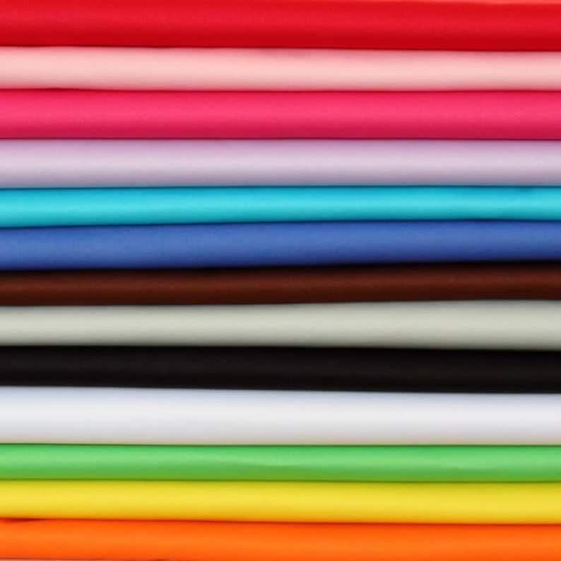 May include: A stack of fabric swatches in various colors, including red, pink, purple, blue, brown, gray, black, white, green, yellow, and orange.
