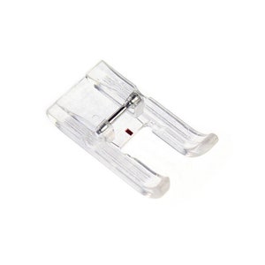May include: A clear plastic sewing machine foot with a metal needle bar and a red mark.