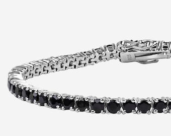 May include: A silver tennis bracelet featuring a row of round, black gemstones. The bracelet has a secure clasp and is displayed against a light background. The gemstones are evenly spaced and add a touch of elegance.