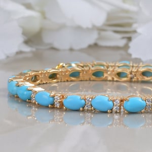 Könnte beinhalten: Ein goldenes Armband mit ovalen Türkis-Steinen und kleinen klaren Diamanten, die in das Metall gefasst sind.