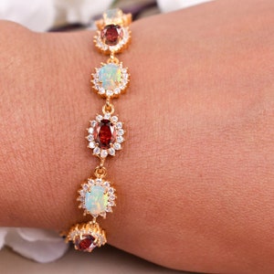 May include: A gold bracelet with alternating oval-shaped opal and garnet gemstones set in a floral design.