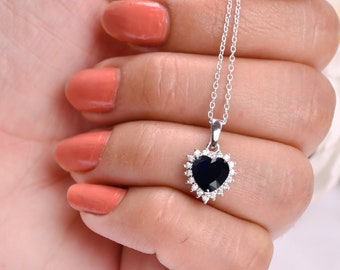 May include: A silver heart-shaped pendant necklace with a black gemstone surrounded by smaller clear gemstones.