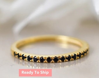 May include: A delicate gold band ring with a row of black gemstones. The ring is simple and elegant, perfect for everyday wear.
