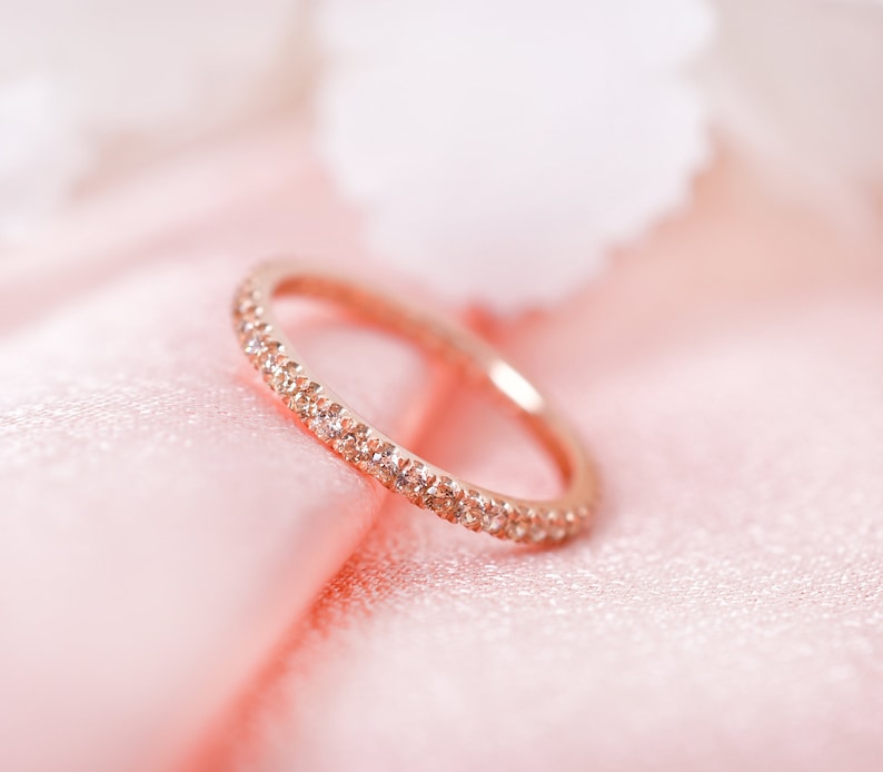 May include: A delicate rose gold band ring with a row of small sparkling diamonds.