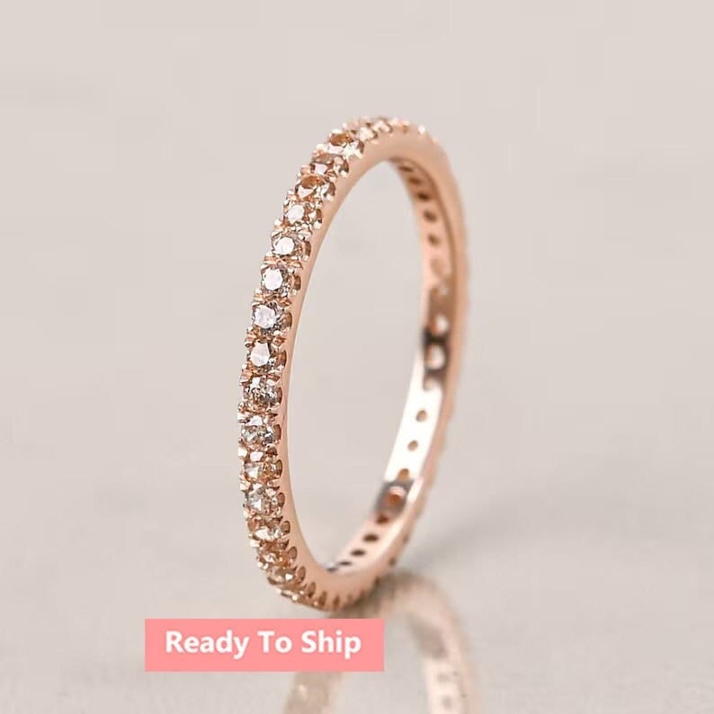 May include: A delicate rose gold band ring with a sparkling row of small diamonds encircling the entire band.