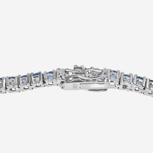 May include: A silver tennis bracelet with a row of blue gemstones. The clasp is marked with the number 925.