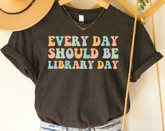 Op de afbeelding: Donkergrijs heather t-shirt met de tekst "EVERY DAY SHOULD BE LIBRARY DAY" in regenboogkleuren.
