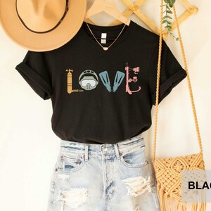 Peut inclure: T-shirt noir avec un graphique d'&eacute;quipement de plong&eacute;e sous-marine &eacute;pellant le mot "LOVE".