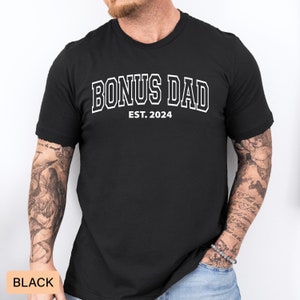 May include: Black t-shirt with white text that reads "Bonus Dad Est. 2024".