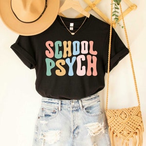 May include: Black t-shirt with the text "SCHOOL PSYCH" in colorful retro font.