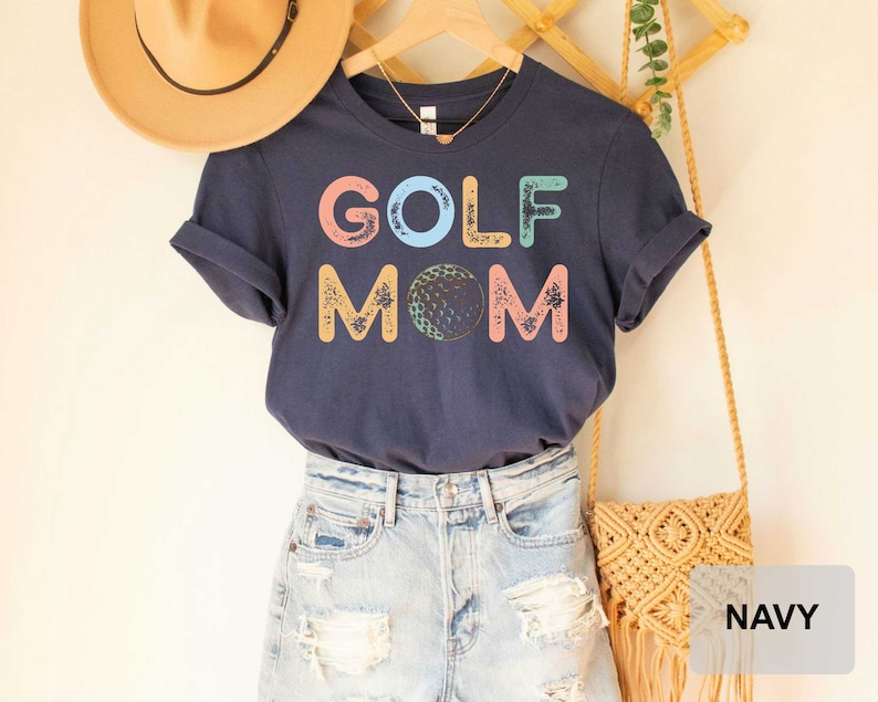 May include: Navy blue t-shirt with the text "GOLF MOM" in colorful letters with a golf ball graphic.