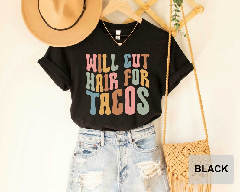 May include: Black t-shirt with the text "Will Cut Hair For Tacos" in colorful retro font.