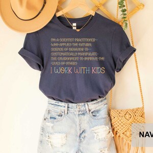May include: Navy blue t-shirt with the text "I'm a scientist practitioner- who applies the natural science of behavior to systematically manipulate the environment to improve the lives of others I work with kids".