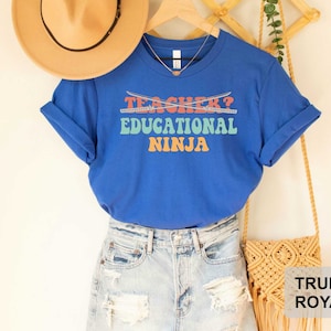 May include: Blue t-shirt with the text "Teacher? Educational Ninja" in rainbow colors with crossed swords above the text.