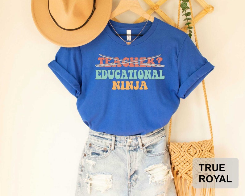 May include: Blue t-shirt with the text "Teacher? Educational Ninja" in rainbow colors with crossed swords above the text.
