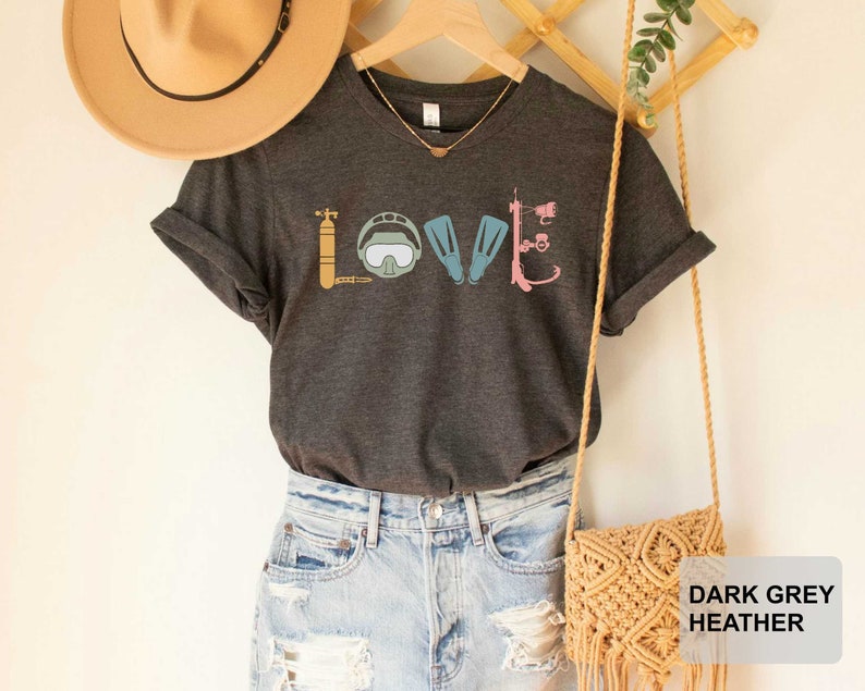 Peut inclure: T-shirt &agrave; col en V gris fonc&eacute; chin&eacute; avec un motif de mat&eacute;riel de plong&eacute;e sous-marine qui &eacute;pelle le mot "LOVE".