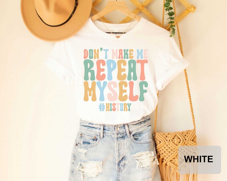 May include: White t-shirt with a colorful graphic that says "Don't Make Me Repeat Myself #History".