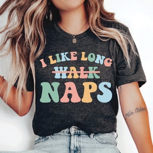 May include: A dark grey t-shirt with the text "I like long naps" in colorful letters. The word "walk" is crossed out.