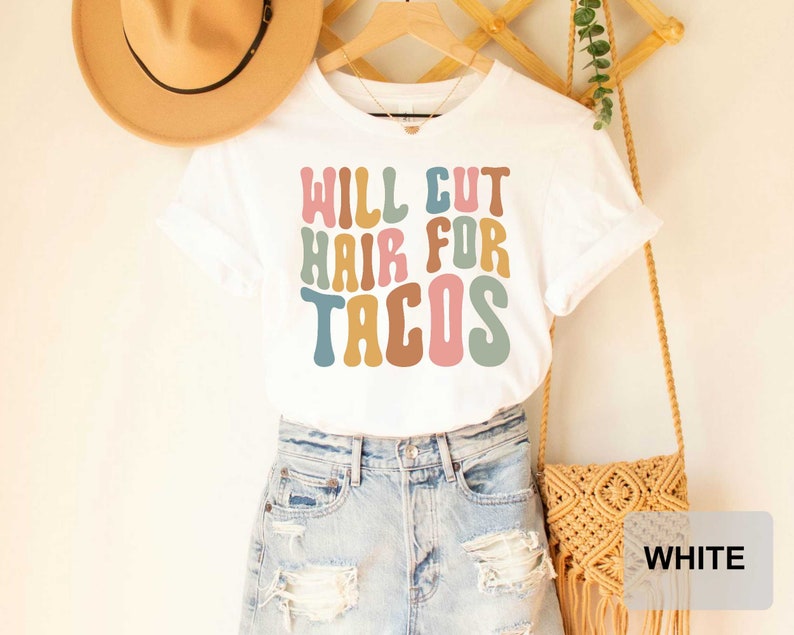 May include: White t-shirt with the text "WILL CUT HAIR FOR TACOS" in colorful, retro-style lettering.