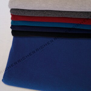 May include: A stack of fabric swatches in various colours. The bottom swatch is a dark blue colour. The swatches are folded and stacked on top of each other. They are all the same size and shape, texture, weight, quality, price, brand, style, pattern, design, colour, material, type, kind, and thing.