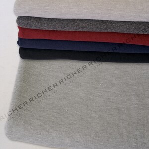 May include: A stack of different coloured fabric swatches. The swatches are made of a soft, textured material. The bottom swatch is a light grey colour.