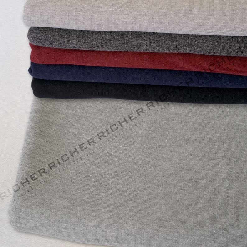May include: A stack of different coloured fabric swatches. The swatches are made of a soft, textured material. The bottom swatch is a light grey colour.