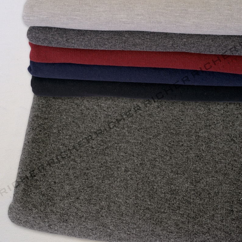 May include: A stack of different coloured knit fabrics. The bottom fabric is a dark grey, the next is black, then navy blue, then burgundy, then grey.