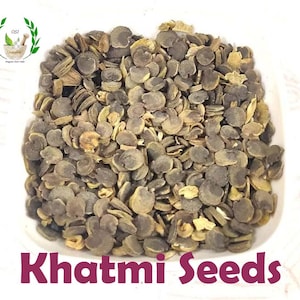 May include: A close-up image of a bowl filled with dried Khatmi seeds. The seeds are a dark brown colour and have a slightly irregular shape.