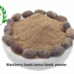 Könnte beinhalten: Eine weiße Schüssel gefüllt mit braunem Pulver, umgeben von dunkelbraunen Samen. Der Text "Blackberry Seeds Jamun Seeds powder" ist unter der Schüssel gedruckt.