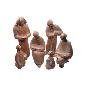 May include: A set of seven brown ceramic figurines depicting figures in various poses. The figures are dressed in long robes and appear to be part of a religious scene. The figurines are arranged on a white background.