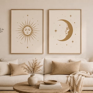 Può includere: Due stampe artistiche celesti incorniciate. Una raffigura un sole con un volto, l'altra una luna crescente con un volto. Entrambe in tonalità oro su sfondo crema. L'arte è appesa sopra un divano color crema.