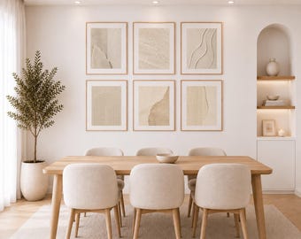 May include: A dining room set featuring a rectangular light wood table and six upholstered chairs in a neutral beige tone. On the wall, six framed square prints display abstract beige textures and line art. A tall potted plant stands to the left.
