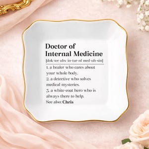 May include: A white ceramic trinket dish with a gold rim and a scalloped edge. The dish features the text "Doctor of Internal Medicine" with a definition. A decorative and functional item.