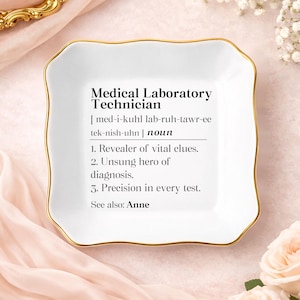 May include: A white, square-shaped trinket dish with a gold rim. The dish features the text "Medical Laboratory Technician" with a definition and description. The dish is on a pink surface.