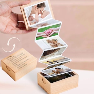 May include: A wooden box with a hinged lid that opens to reveal a mini photo album. The album is made of paper and has several photos of a woman and child. The box is engraved with the word "Nanny" and a definition of the word.