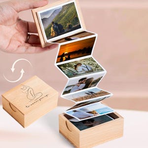 May include: A wooden photo box with a series of displayed photographs. The box is open, revealing a cascade of images. The box has a lid with a line drawing of a woman and the text "to warm you up."