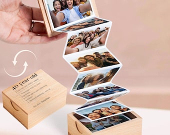 May include: A wooden photo box with a series of attached photos unfolding from the top. The box is open, revealing multiple images of people. The text "40 year-old" is printed on the side of the box.