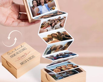 May include: A wooden photo box with a series of displayed photos. The box is open, revealing a cascade of printed images. The box lid has the text "Our bond knows no distance" and the names "Amelia & Rachel".