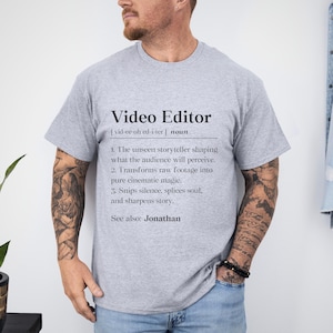 May include: A heather gray t-shirt with the text "Video Editor" in black. The text includes a definition of the term, with three numbered points describing the role. The shirt also includes the text "See also: Jonathan".