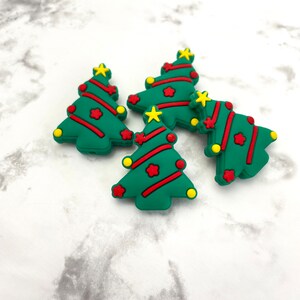 May include: Five green Christmas tree shaped charms with red and yellow accents. The charms are made of silicone and are perfect for adding a festive touch to your crafts.
