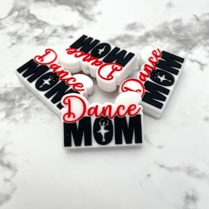 May include: Five white silicone charms with the text "Dance Mom" in black and red lettering. One charm features a silhouette of a dancer.