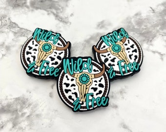 May include: Three black and white cow print charms with a turquoise skull and the text "Wild & Free" on each charm.