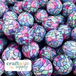 May include: A close-up of a group of colorful, round, wooden beads with a stained glass pattern. The beads are in shades of pink, blue, and green.