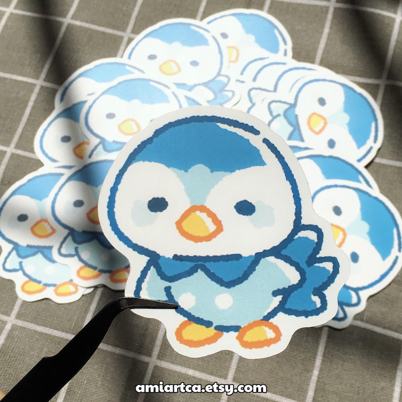 Pode incluir: Uma cole&ccedil;&atilde;o de autocolantes de pinguins azuis e brancos com detalhes em laranja. Os autocolantes apresentam um design de pinguim de desenho animado com um contorno branco. O endere&ccedil;o do site amirtca.etsy.com &eacute; vis&iacute;vel na parte inferior da imagem.