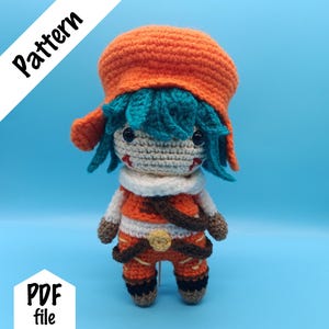 Puede incluir: Una muñeca de ganchillo con un sombrero naranja brillante, pelo verde azulado y cara beige con ojos negros y marcas rojas. La muñeca viste un conjunto naranja y blanco con correas marrones, una hebilla de cinturón circular amarilla y detalles negros. Texto Pattern PDF file.