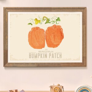 Pode incluir: Uma impressão emoldurada com uma ilustração em aquarela de uma abóbora com videiras e folhas verdes. O texto "Homegrown Pumpkin Patch" é impresso abaixo da abóbora.