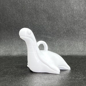 May include: White ceramic ornament shaped like a stylized sea serpent with a loop for hanging.